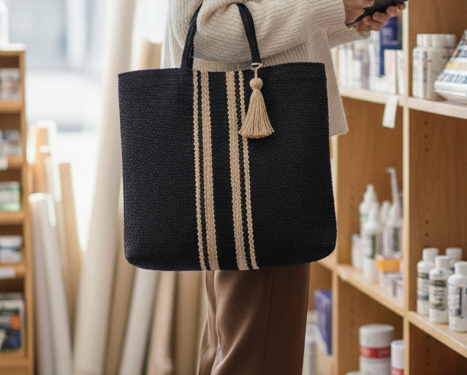 A navy jute tote bag with two tan stripes running vertically down the tote.