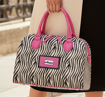 A zebra print bag with pink handles and a pink brand label on it, in a person's hand.