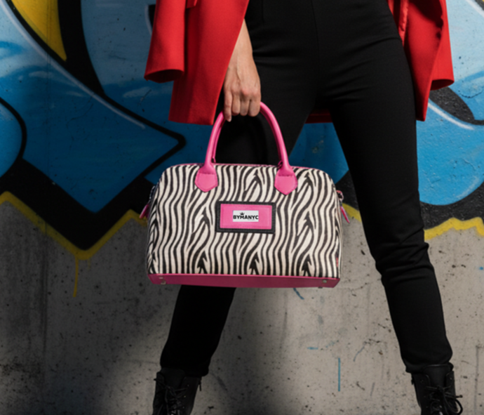 Woman in red coat holding a zebra-patterned tote against a graffiti-covered wall.