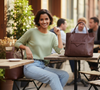 Woman sitting at an outdoor cafe table with a brown vegan leather tote bag.