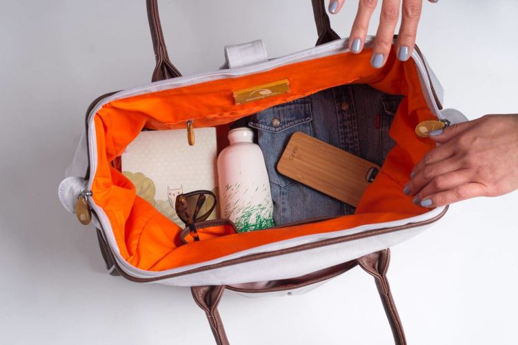 Person packing items into an open suitcase with an wire frame and orange interior.