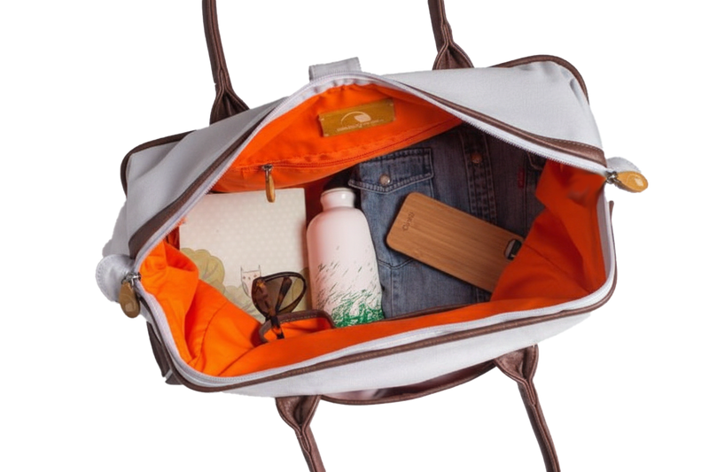 Open handbag with orange interior showing a bottle, sunglasses, and denim item.