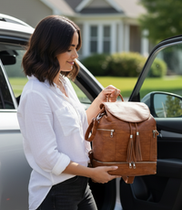 Woman holding a brown vegan leather convertible backpack diaper tote bag  next to a car