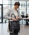 Woman in a professional setting opening a black handbag.