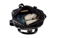 Black puffer weekender tote with shoes and clothes inside on a white background