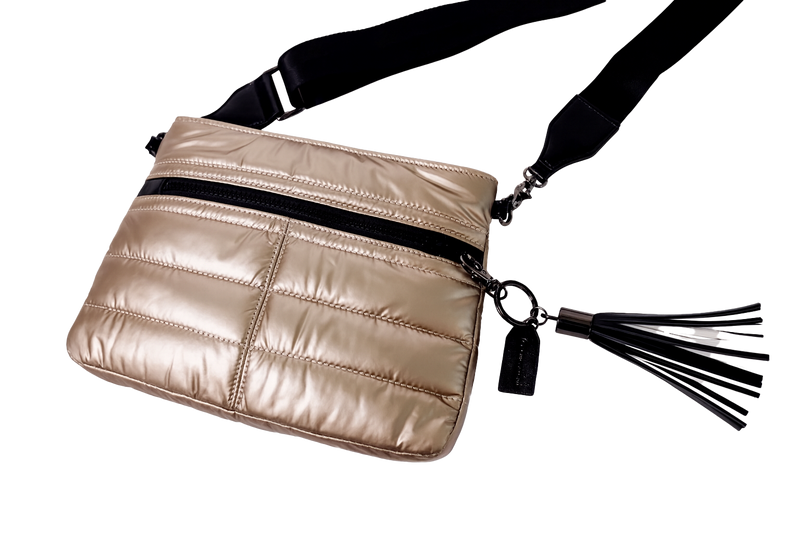 Gold metallic crossbody bag with a black tassel on a white background