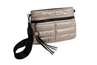 Beige quilted handbag with black strap and tassel on a white background