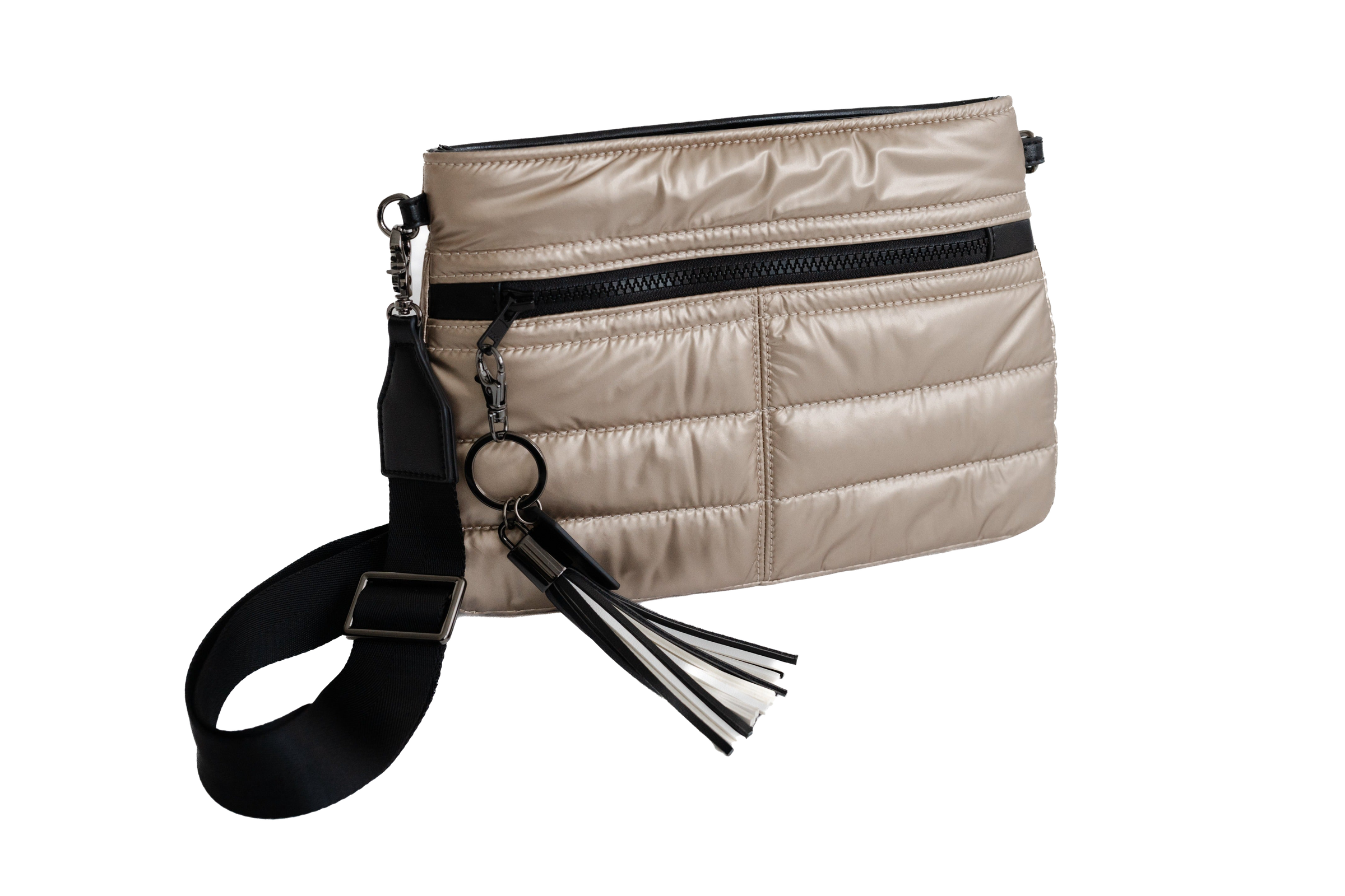 Beige quilted handbag with black strap and tassel on a white background