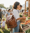 Woman with a brown vegan leather convertible backpack diaper tote bag at an outdoor farmer's market