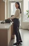 Woman standing in a modern kitchen with a window in the background and a green tote