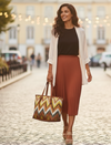 Woman walking down a street holding a woven patterned tote