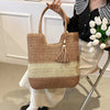 Person holding a woven tote with a tassel, sitting on a chair indoors.