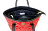 Red patterned woven tote with black interior and gold zipper on a white background