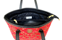Red patterned woven tote with black interior and gold zipper on a white background