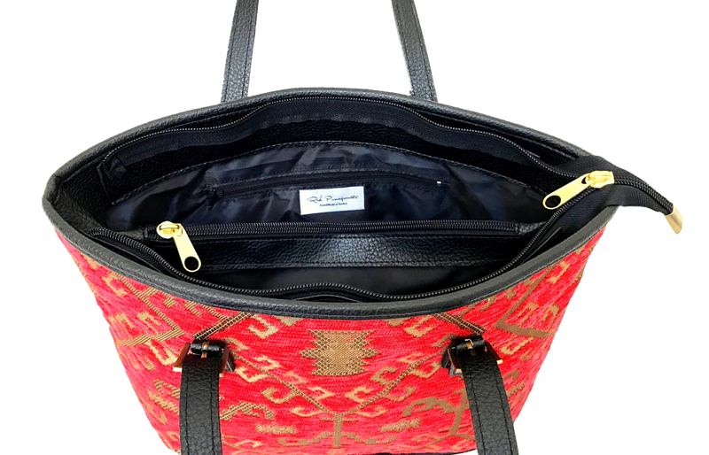 Red patterned woven tote with black interior and gold zipper on a white background