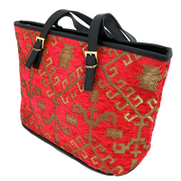 Red patterned woven tote with gold patterns and black handles on a white background