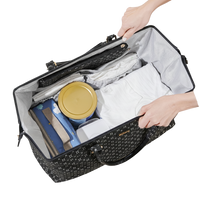 Black patterned diaper bag tote with contents including a yellow container and blue item, held open by hands.
