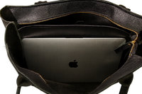 Black leather tote bag with a laptop inside, featuring the Apple logo.