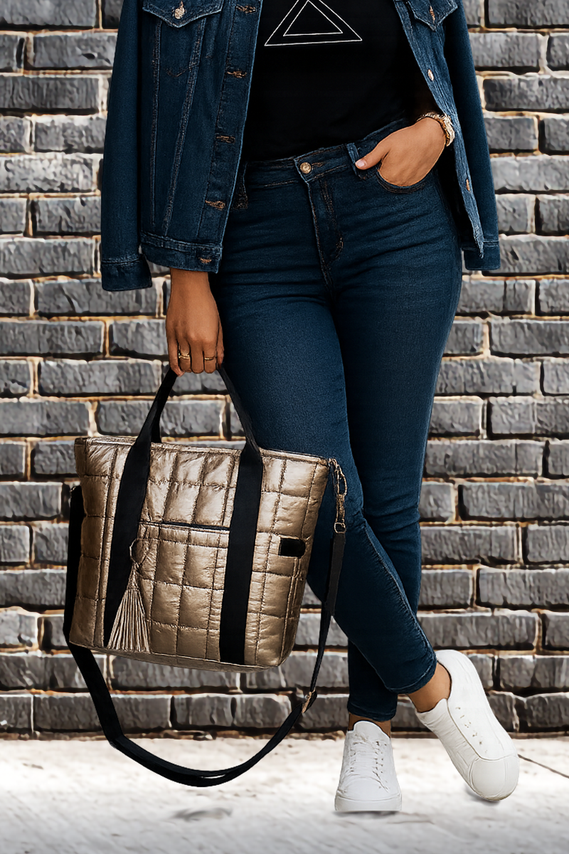 Woman holding a gold laptop tote against a brick wall