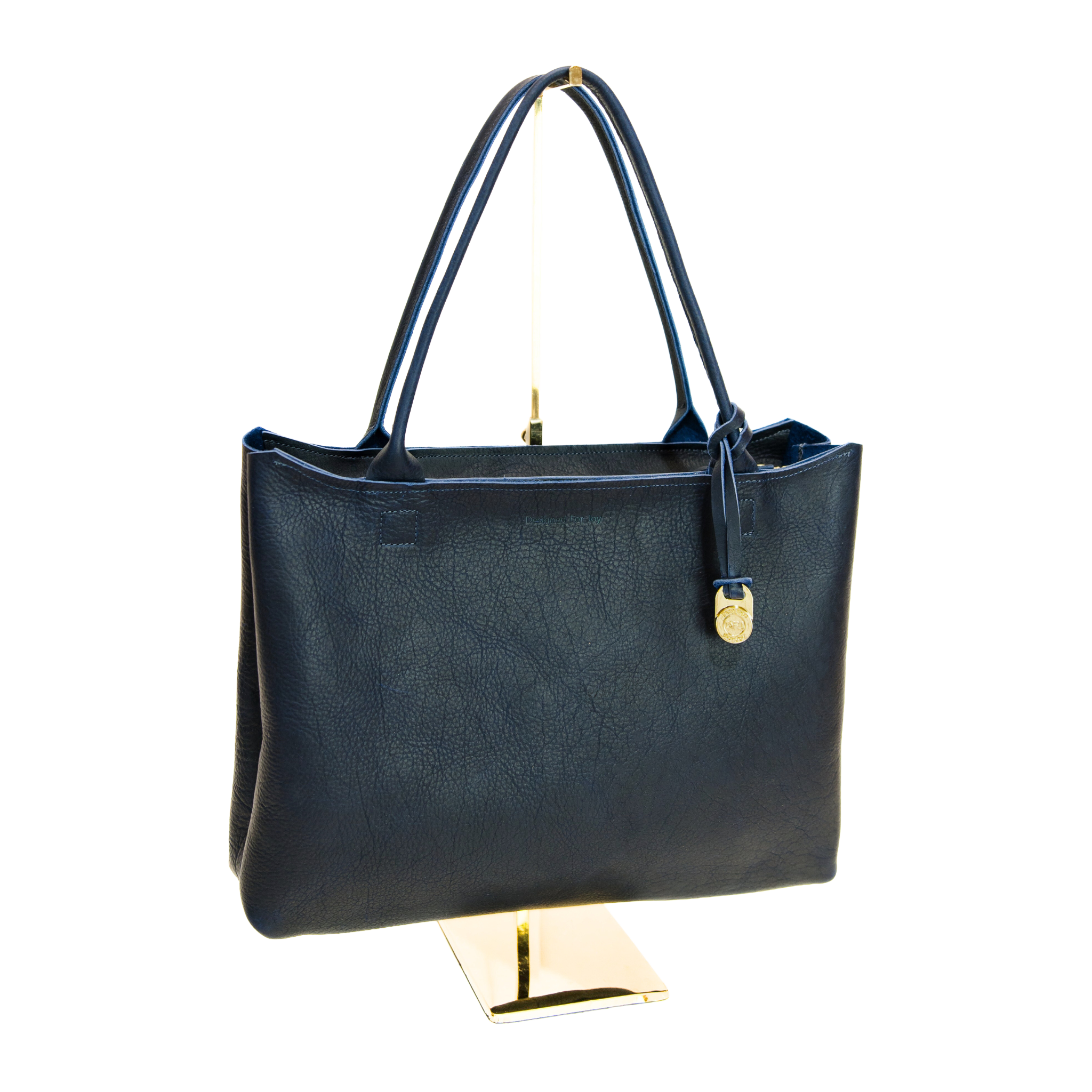 Navy handbag on a gold stand against a white background