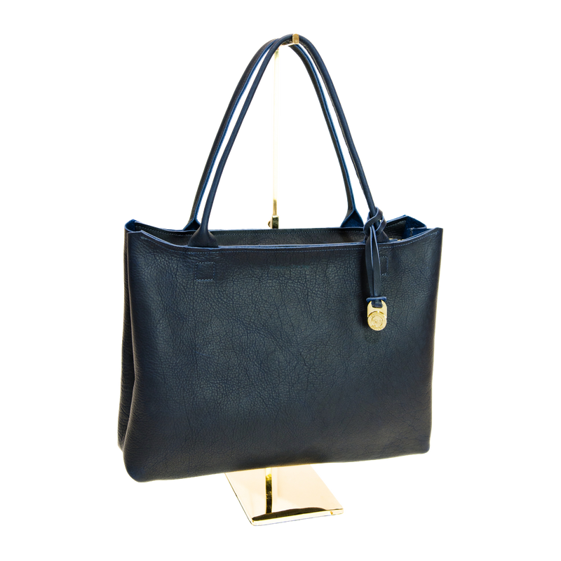 Navy handbag on a gold stand against a white background