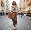 Woman walking down a city street holding a brown tote bag