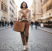 Woman walking down a city street holding a brown tote bag