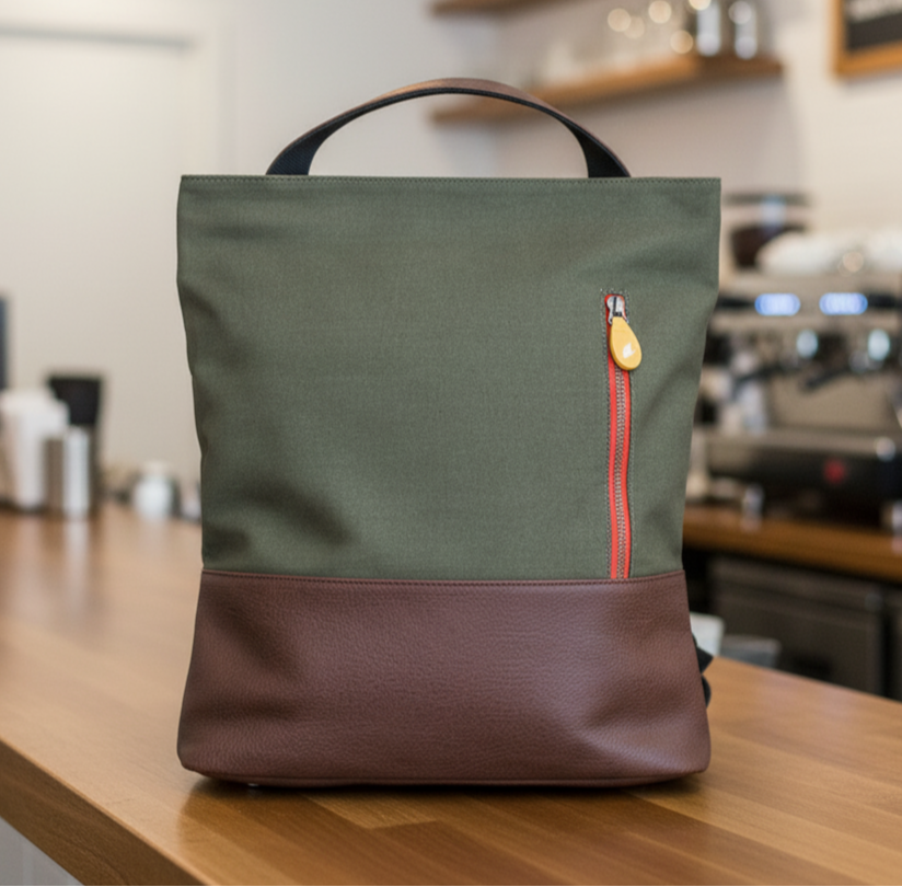 Green and brown convertible tote bag backpack on a wooden counter in a cafe setting