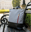 Gray convertible 3-in-1 backpack tote bag with a red zipper on a wooden bench in an outdoor setting