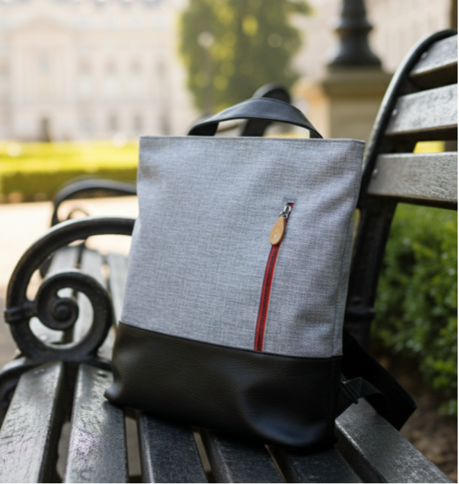 Gray convertible 3-in-1 backpack tote bag with a red zipper on a wooden bench in an outdoor setting