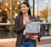 Woman holding a gray and brown convertible tote backpack bag outdoors