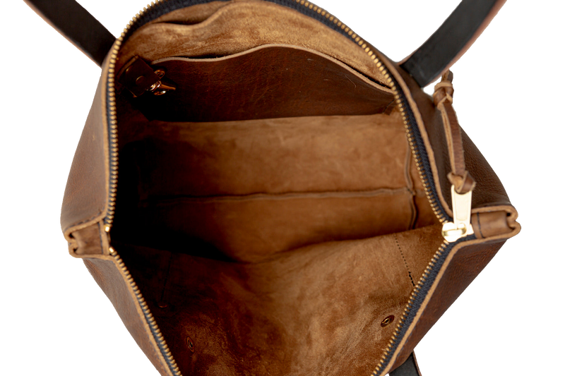 Brown leather tote with brass zipper on a white background
